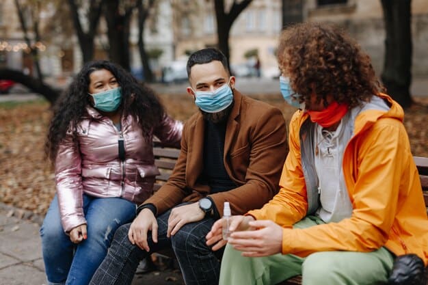 A diverse group of people wearing face masks and maintaining social distance in a public park, illustrating community adherence to health guidelines.
