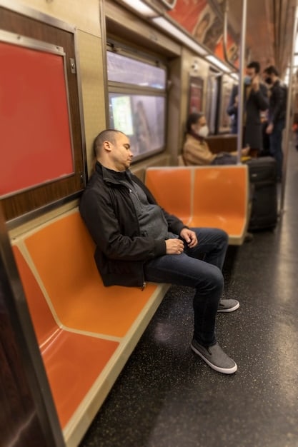 A person meditating briefly on a subway or bus, demonstrating how to find mindful moments in a busy, urban environment.
