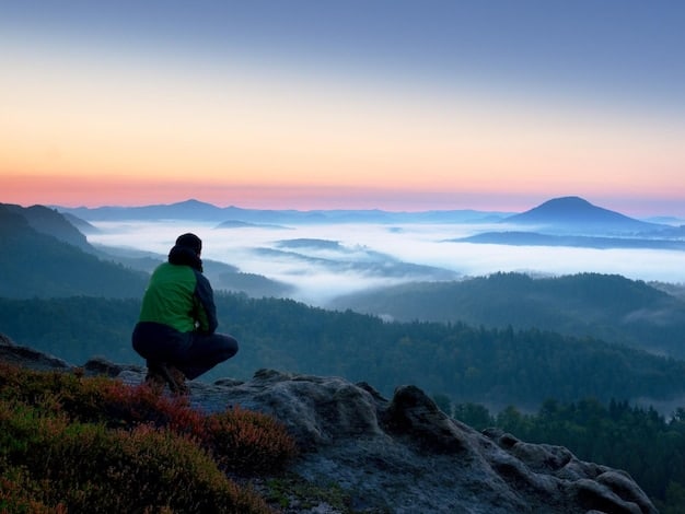 A serene person meditating outdoors during sunrise, surrounded by misty mountains, conveying peace and mental clarity.