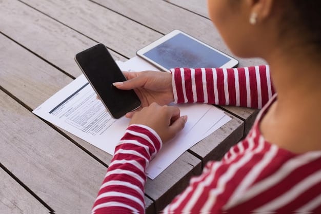 A close-up of a hand holding a smartphone, registering for FEMA assistance online. The screen displays a government website with forms for disaster relief, emphasizing digital accessibility.